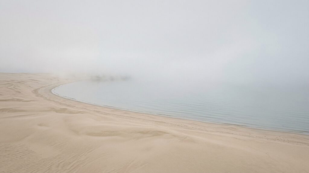 soft fog over a calm ocean merging with a sandy desert